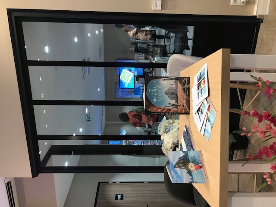 Espace d'accueil Carrefour Voyages — magazines Traveller et clients en arrière-plan, invitant à la conversation